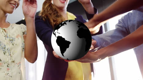 animation of globe rotating over happy diverse colleagues stacking hands at casual office