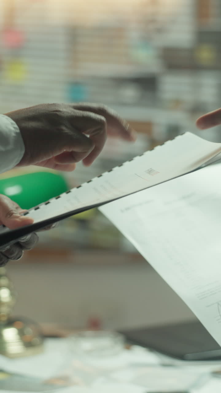 Close-up of Hands Reviewing Documents and Pointing in an Office