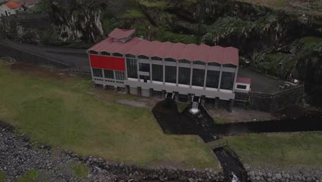 Aerial-view-of-an-hydroelectric-power-plant-on-the-river-mouth,-drone-moving-forward-in-direction-of-the-power-plant-and-camera-tilting-down