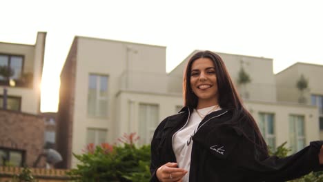 Una-Joven-Positiva-Está-Mirando-La-Puesta-De-Sol-De-La-Hora-Dorada-Haciéndola-Sentir-Bien-Disfrutando-De-La-Vida-Luciendo-Linda-Fabulosa-Sonriendo-Sacando-La-Lengua-Descarada-Confiada-En-Las-Casas-Barrio-Rico