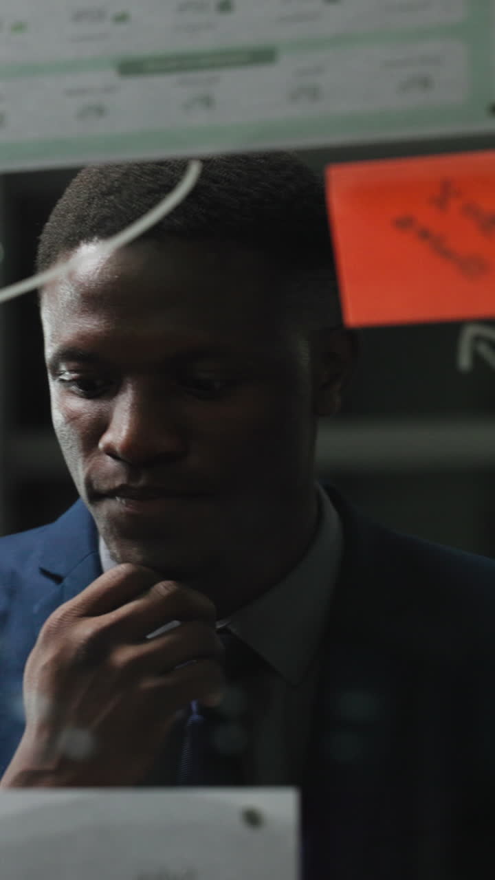 Young Businessman Thinking and Analyzing Ideas on a Glass Board