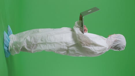 아시아 남성 과학자가 노트북으로 타이핑하고 녹색 화면 배경에서 주위를 둘러보는 전체 몸의 측면 시각