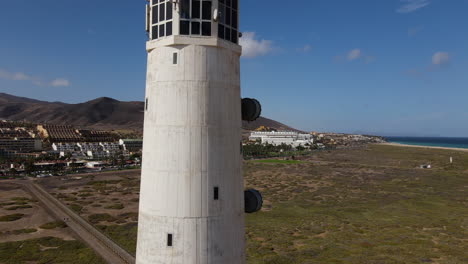 toma aérea en un día soleado del faro de morro jable viajando verticalmente hasta llegar al final del faro