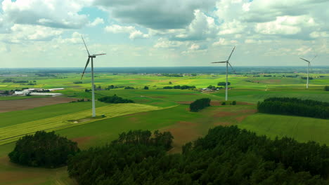aerial footage showing three wind turbines standing tall over a vast rural landscape with fields and trees