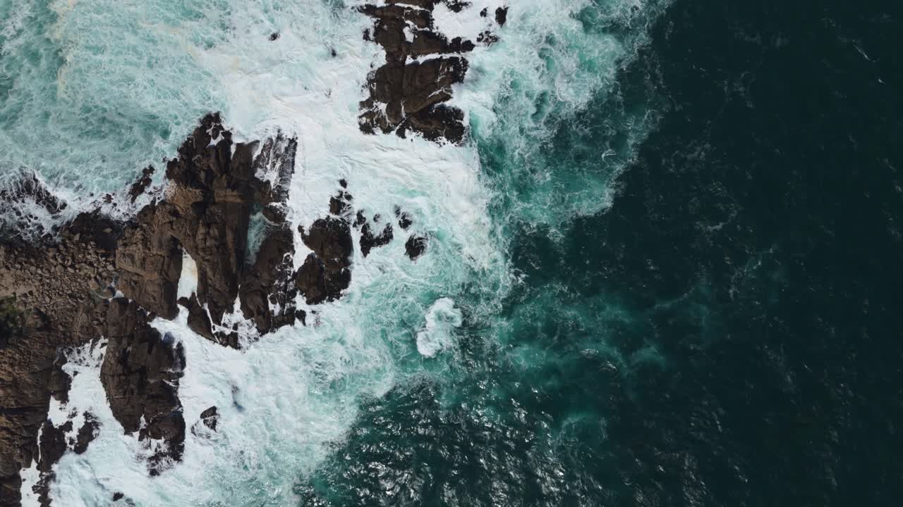 Aerial birds eye view showcasing powerful ocean waves crashing against the rocky coastline at Playa Chica, Quintay in Valparaíso, Chile. Push Forward Shot