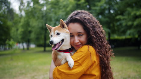 woman hugging a shiba inu dog in a park