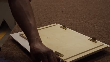 cabinet maker using a power drill to attach hinges and brackets to cabinet doors