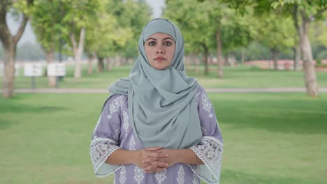 serious muslim woman looking at the camera in park