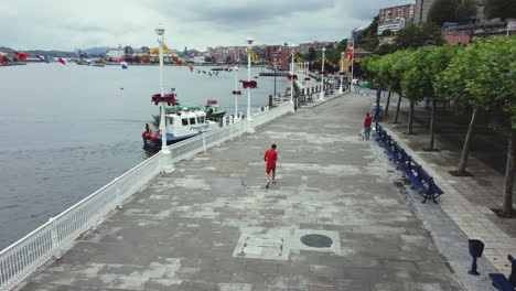 paseo marítimo costero con botes fluviales y personas caminando