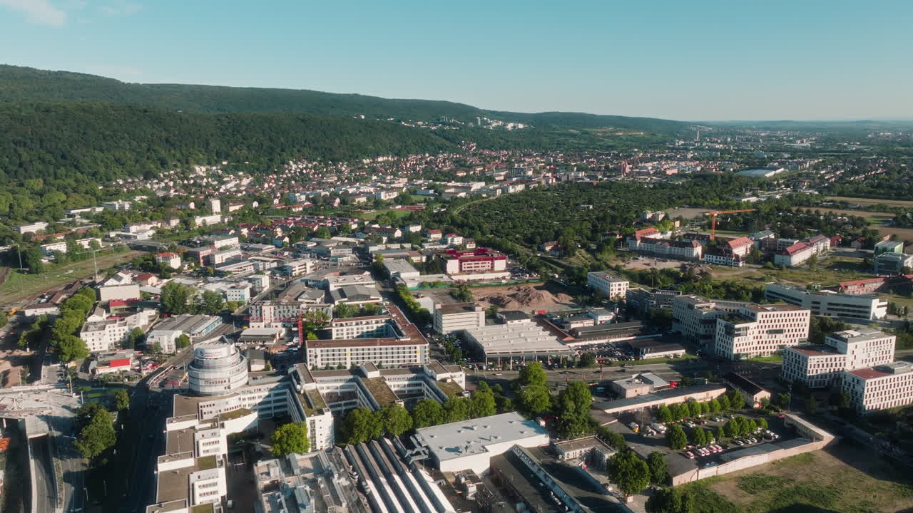 Drone orbiting view of Heidelberg’s cityscape with hills and dense forest behind