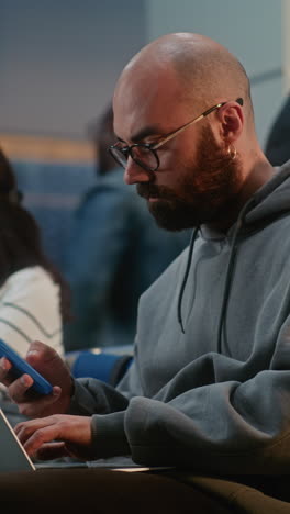 man working on laptop and smartphone