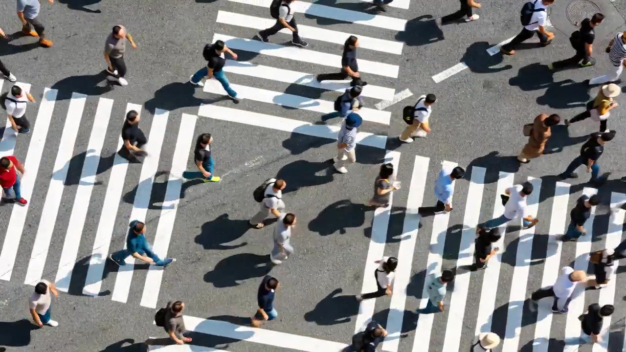 Walking commuters heading across Shibuya zebra stripes after pedestrian signal changing for work