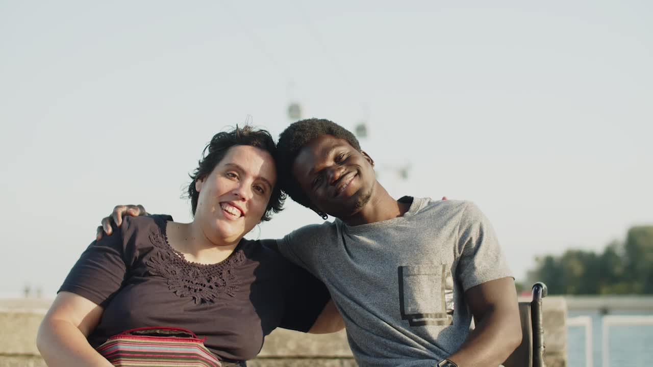 Pareja feliz en sillas de ruedas abrazándose y apoyando las cabezas