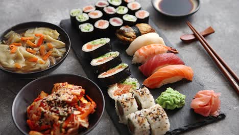 composición de diferentes tipos de rollos de sushi colocados en tablero de piedra negra