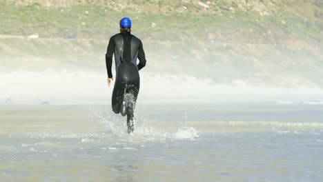 ビーチで走っている男性サーファーの後ろの景色