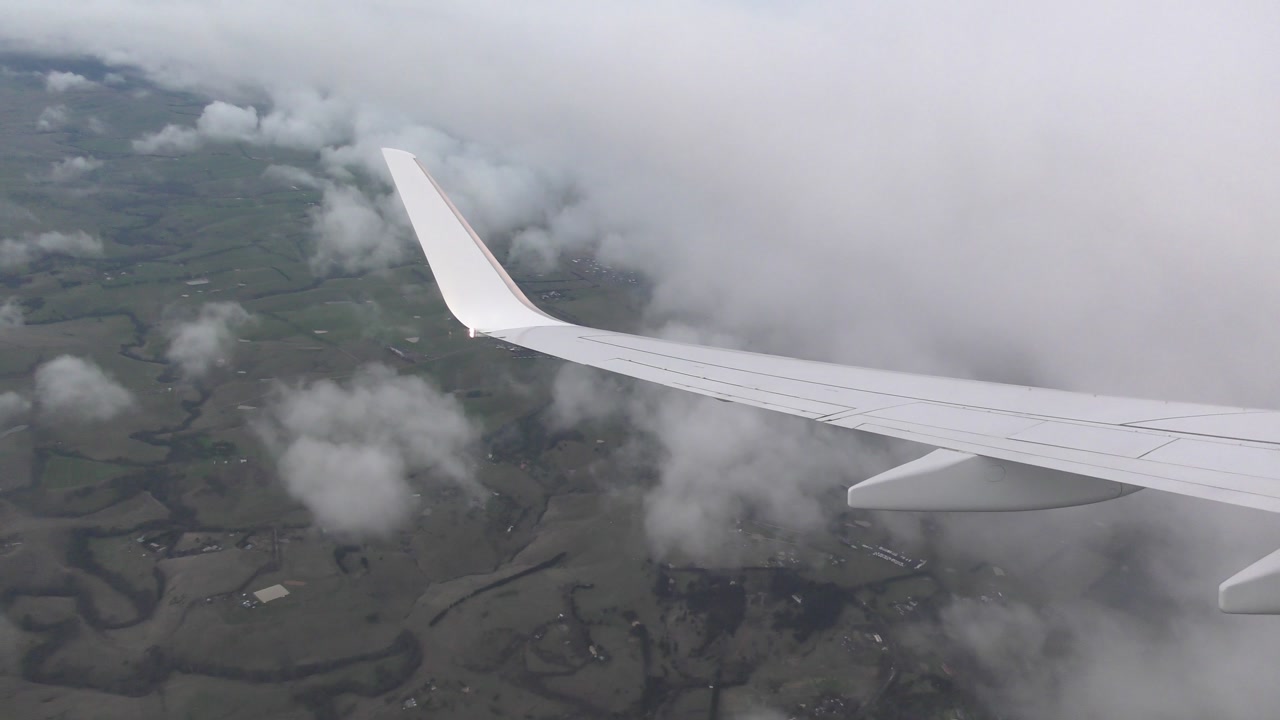 Plane wing view over land then into clouds in 4K. Ideal for travel or aerial projects. Shot in H.264, 25 frames per second, 15 seconds. No model release needed. License this scenic stock footage.