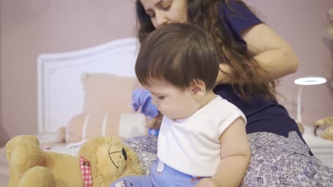 la madre está vistiendo a su bebé.