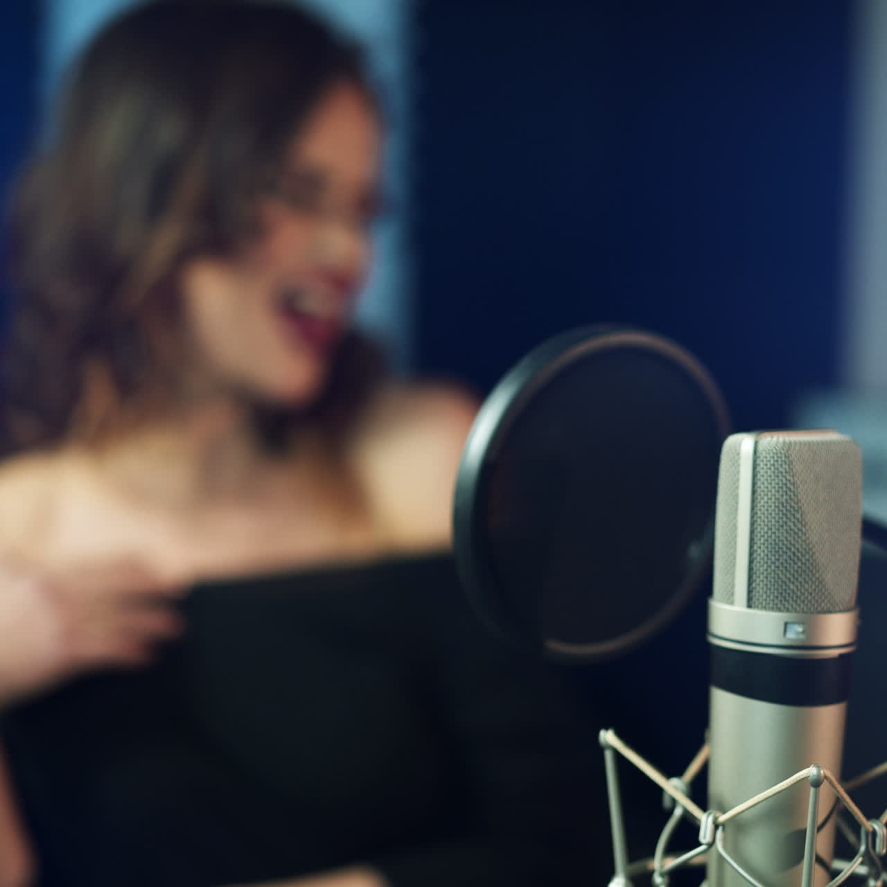 Professional microphone in the recording studio. Singing woman in the background Square video