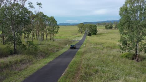 drone shot tracking car driving away from camera on country road, stationary camera