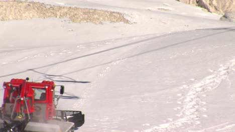 snow groomer enters frame, preparing and smoothing pistes atski centre, static shot.