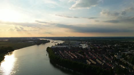 Silhouette-Von-Zwei-Booten,-Die-Entlang-Beneden-Merwede-In-Der-Ferne-Mit-Goldenem-Orangefarbenem-Sonnenuntergangshimmel-Segeln