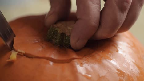 removing top from a ripe fresh pumpkin with a knife