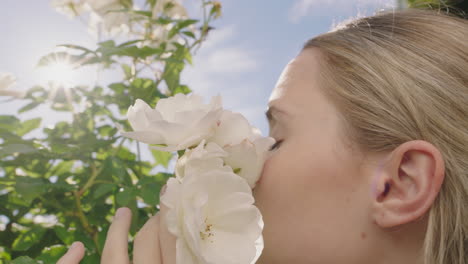 cerca una mujer hermosa oliendo rosas floreciendo en el jardín de rosas disfrutando del olor natural