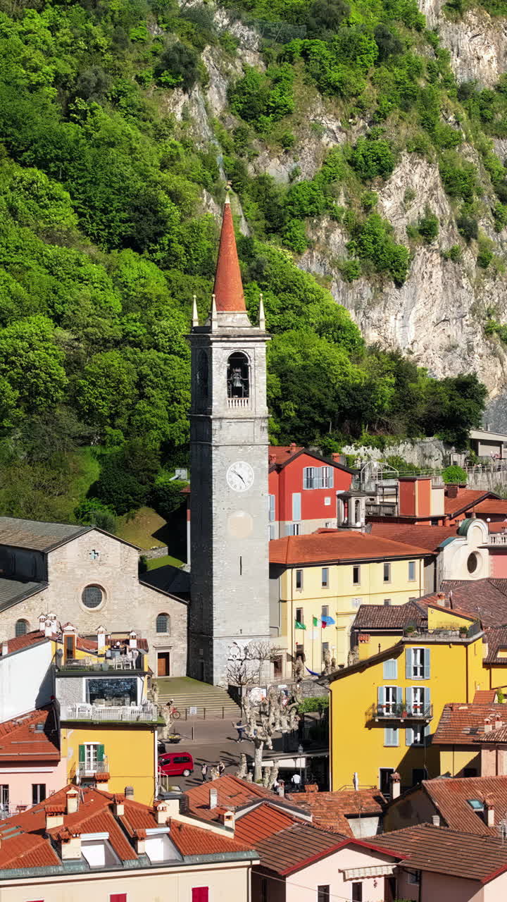 Aerial drone view of Church of S.Giorgio surrounded by houses in Varenna, Italy. Vertical