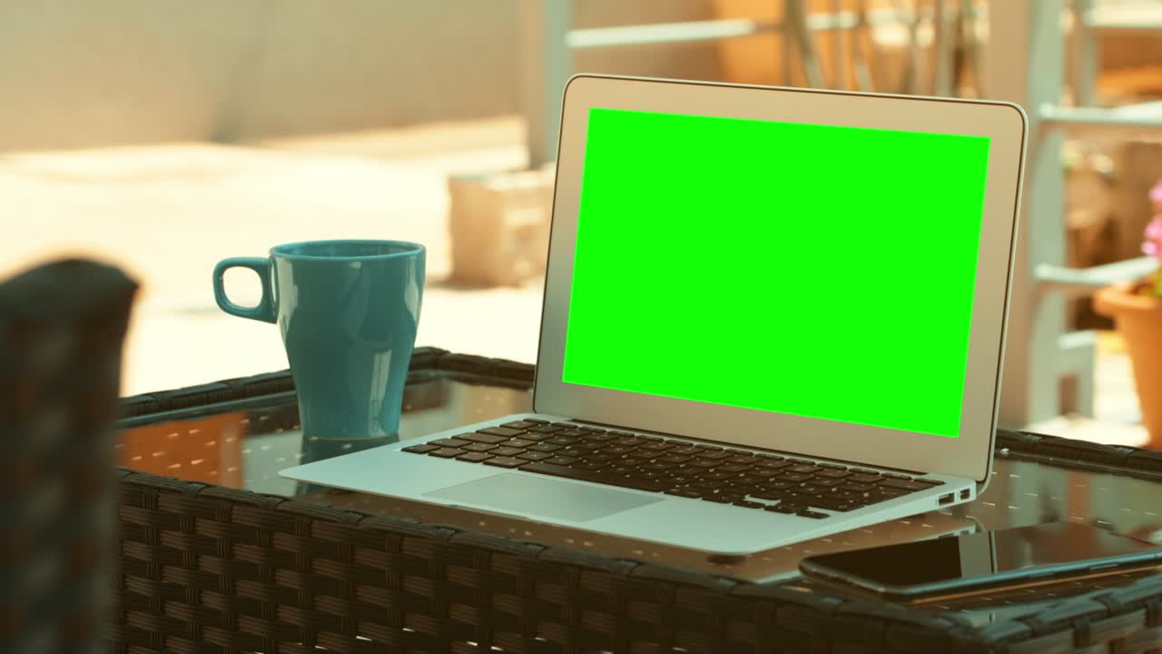 pantalla verde de maqueta de portátil en el balcón de la casa en la mañana de verano