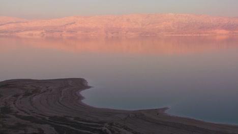 a high and wide shot of the shoreline of the dead sea in israel at dusk