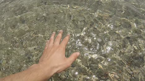 a boy's hand touching the sea