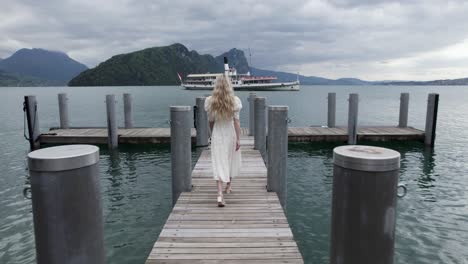 Woman-on-Lake-Lucerne-Pier-Dock-with-Ferry-Boat,-Aerial-Tracking