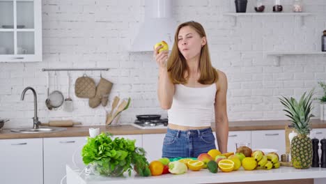 smiling housewife at home. sporty young woman eating healthy food in light kitchen