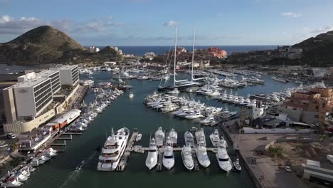 Boats-docked-at-marina-along-the-boardwalk-in-Cabo,-Mexico,-establishing-aerial-view