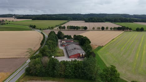 aerial view of red barn of traditional amish farmstead in united states. cloudy summer day with bright landscape. street between cropland and farmland.wide shot. iowa, midwest, usa