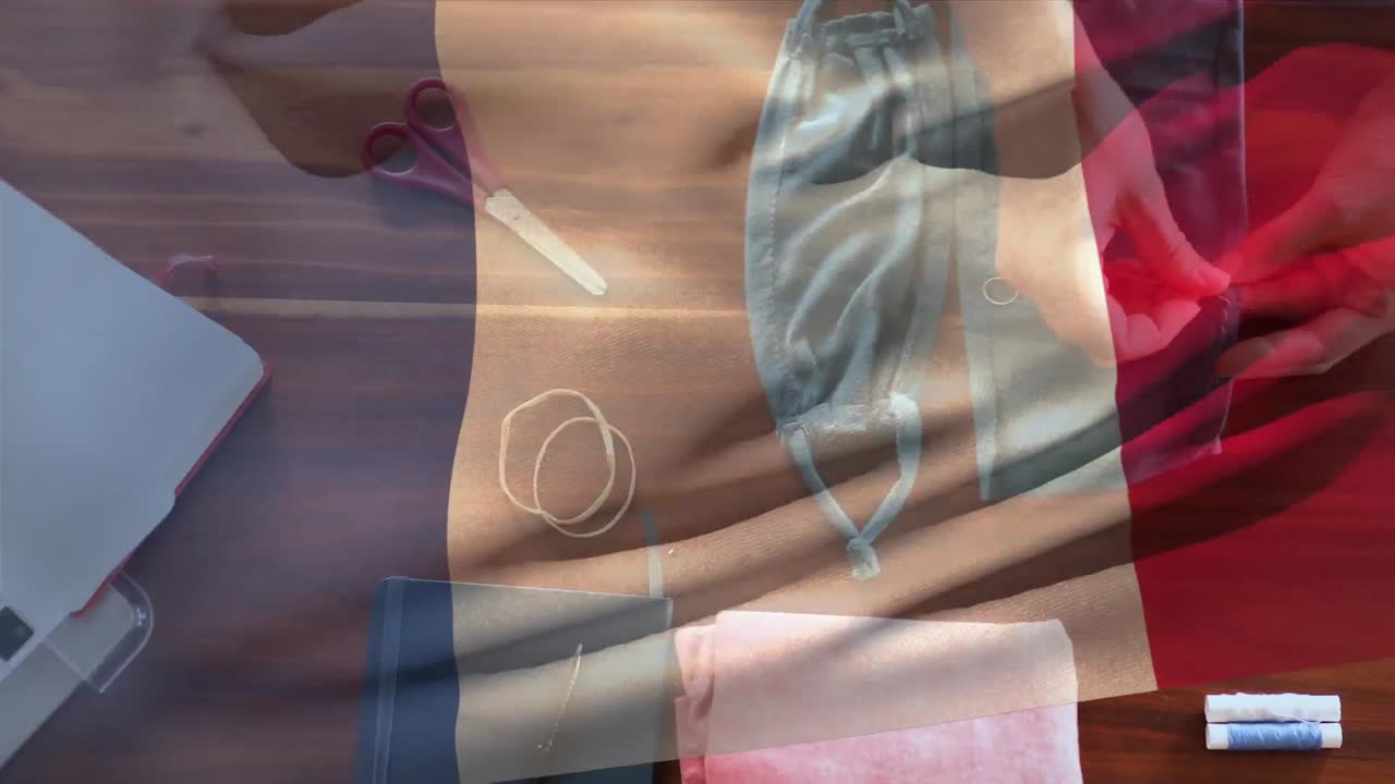 bandera francesa ondeando contra la sección media de la mujer cosiendo una máscara facial
