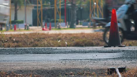 large steam roller flattening a newly laid road surface by a traffic cone