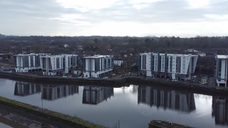 early morning aerial view riverside waterfront contemporary apartment office buildings canal regeneration real estate slow right dolly