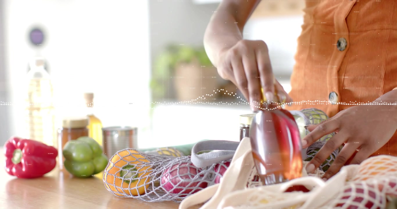Woman smoothing bag then unpacking food in kitchen pulling bell pepper and inspecting syrup bottle