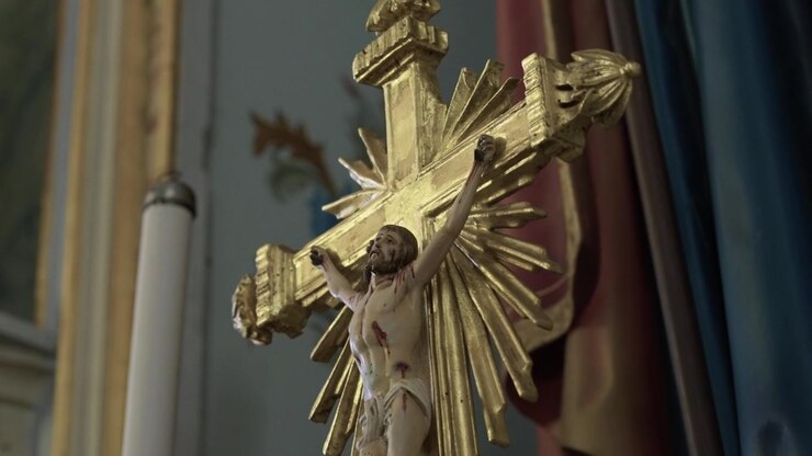 Crocifisso intagliato di Gesù Cristo su una croce dorata con raggi solari radiosi su un altare di chiesa