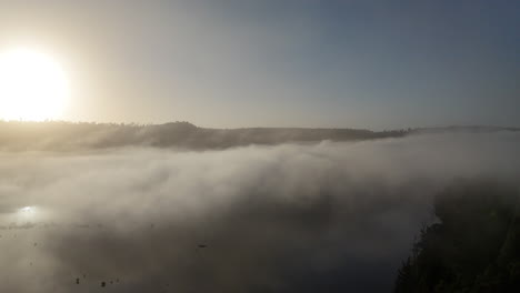 witness a breathtaking sunrise breaking through clouds as a drone ascends over a tranquil landscape, revealing the beauty of dawn in the mist.