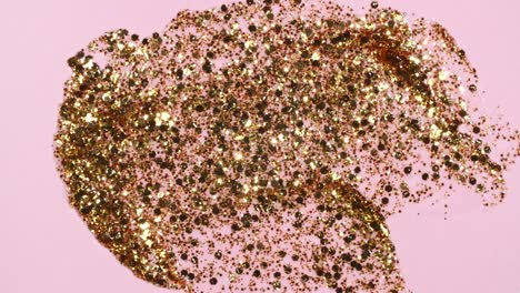 brushstrokes of gold paint brush applied isolated on a pink background. gold paint smear texture. shine, stars, sparkles. golden sparkling textured artistic illustration. smears of cosmetics.