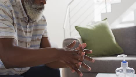 Senior-man-sanitizing-his-hands-at-home