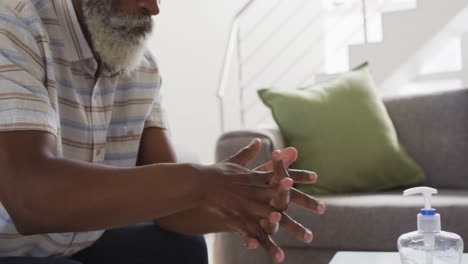 Senior man sanitizing his hands at home
