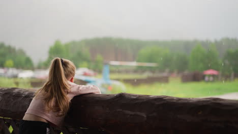 little kid leans on old log railing and looks at helicopter