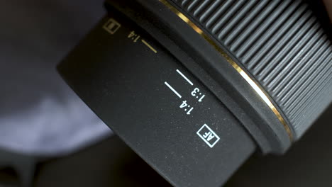 un primer plano de una lente de cámara dslr de apertura fija, el anillo de enfoque gira a medida que extiende el núcleo de la lente que está marcado con una escala de distancia y se utiliza como ayuda para enfocar al sujeto