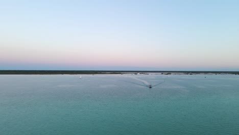 Gran-Angular-Que-Establece-Una-Toma-De-Drones-De-Una-Hermosa-Escena-De-La-Laguna-De-Siete-Colores-Durante-La-Puesta-De-Sol-Con-Yates-Y-Veleros-Que-Regresan-Al-Muelle-Ubicado-En-Bacalar,-México-En-4k