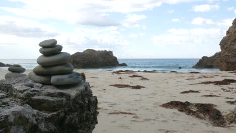 fotografía de mano de una pila de rocas meditativas con el océano y las olas en el fondo