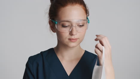 redheaded doctor in front of camera on gray background.