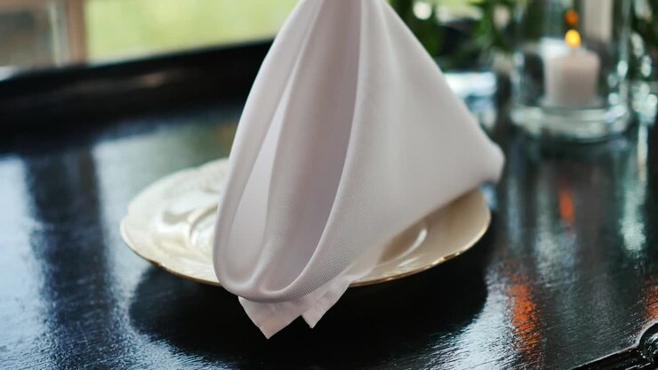 Folded white napkin on plate on wedding table